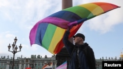 FILE - A participant waves a rainbow flag during an LGBT community rally in central Saint Petersburg, Russia, Aug. 3, 2019.