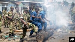 Des militaires et des policiers poussent de leur pieds un tronc d'arbre pour dégager une barricade érigée par des manifestants ans le district de Cibitoke, à Bujumbura, Burundi, lundi 25 mai 2015