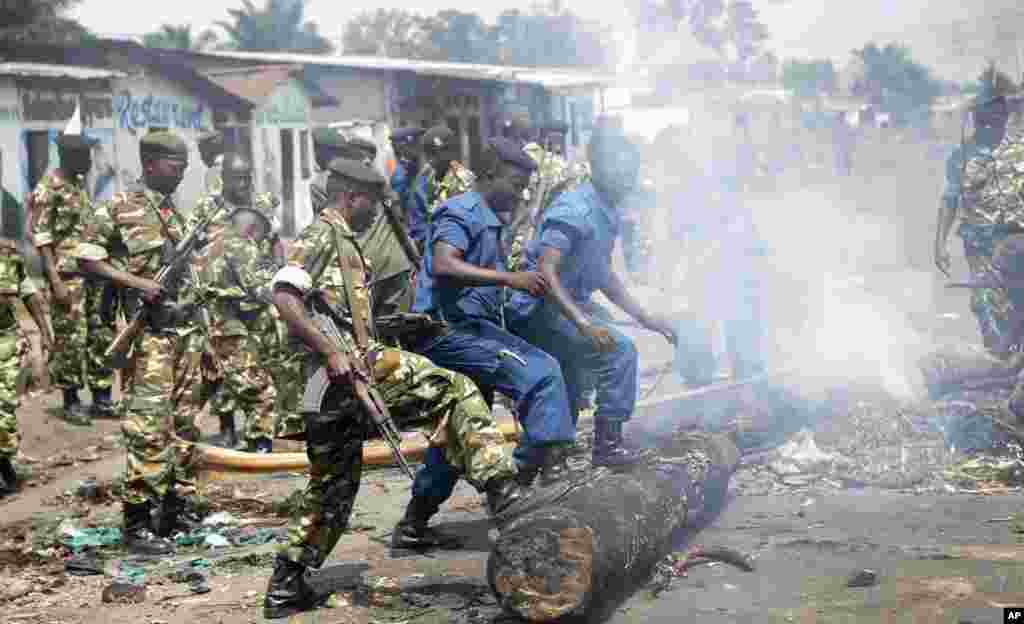 Des militaires et des policiers poussent de leurs pieds un tronc d&#39;arbre pour dégager une barricade érigée par des manifestants ans le district de Cibitoke, à Bujumbura, Burundi, lundi 25 mai 2015