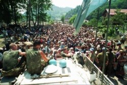 FILE - A Thursday July 13, 1995 photo from files showing Dutch UN peacekeepers sitting on top of an APC while Muslim refugees from Srebrenica, eastern Bosnia, gather in the village of Potocari