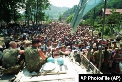 FILE - A Thursday July 13, 1995 photo from files showing Dutch UN peacekeepers sitting on top of an APC while Muslim refugees from Srebrenica, eastern Bosnia, gather in the village of Potocari
