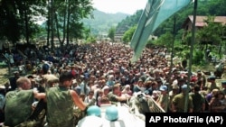 Fotografija od četvrtka, 13. jula 1995. godine, prikazuje holandske mirovne snage UN-a kako sjede na oklopnom transporteru dok se muslimanske izbjeglice iz Srebrenice, istočna Bosna, okupljaju u selu Potočari