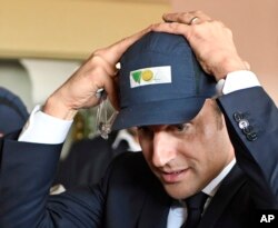 French presidential election candidate for the En Marche! movement Emmanuel Macron, adjusts his cap during a visit to a glass-making company as part of a campaign trip in Albi, southwestern France, May 4, 2017.