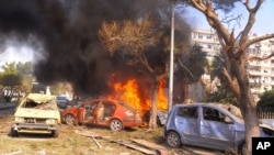 This photo released by the Syrian official news agency SANA, shows flames and smoke rising from burned cars after a huge explosion that shook central Damascus,February 21, 2013. 