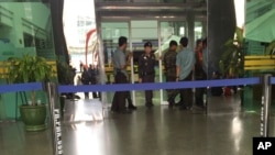 Police officers and others gather in front of the entrance of Phramongkutklao Hospital, a military-owned hospital that is also open to civilians, as people evacuated sit outside in Bangkok after a bomb wounded 24 people, in Bangkok, May 22, 2017