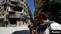 A Shi'ite fighter holds his weapon while patrolling a road at Sayeda Zainab area in Damascus, May 26, 2013.