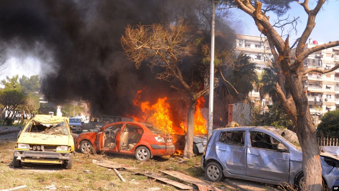 This photo released by the Syrian official news agency SANA, shows flames and smoke rising from burned cars after a huge explosion that shook central Damascus,February 21, 2013. 