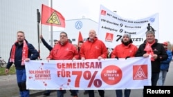 FILE - Employees of Volkswagen AG march for higher wages in front of the Osnabrueck Volkswagen plant during a 'warning strike' of Germany's IG Metall metalworkers' union, in Osnabrueck, Germany, November 6, 2024.