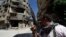 A Shi'ite fighter holds his weapon while patrolling a road at Sayeda Zainab area in Damascus, May 26, 2013.