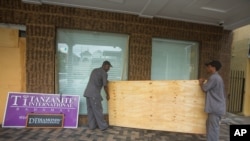 Two men carry a sheet of plywood as they cover the windows of the Diamond's International store, in preparation for the arrival of hurricane Joaquin in Nassau, Bahamas, Thursday, Oct. 1, 2015.