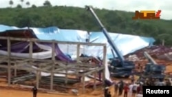 Watu wakitazama paa lililoporomoka la kanisa mjini Uyo, Nigeria