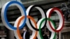 Un homme portant un masque passe devant l'anneau olympique des Jeux olympiques, Japon, le 12 juillet 2021.