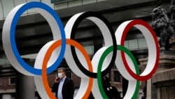 Un homme portant un masque passe devant l'anneau olympique des Jeux olympiques, Japon, le 12 juillet 2021.