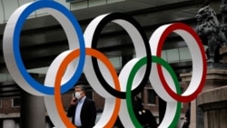 အိုလံပစ်ပြိုင်ပွဲ ကျင်းပမယ့် ဂျပန်နိုင်ငံ တိုကျိုမြို့က အိုလံပစ်သင်္ကေတအနီး ဖြတ်သန်းသွားလာသူတဦး။ (ဇူလိုင် ၁၂၊ ၂၀၂၁)