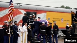 The flag-draped casket of former President George H.W. Bush is carried by a joint services military honor guard as it is placed on a Union Pacific train in Spring, Texas, Dec. 6, 2018. 