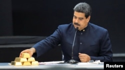 FILE - Venezuela's President Nicolas Maduro touches a gold bar as he speaks during a meeting with the ministers responsible for the economic sector at Miraflores Palace in Caracas, Venezuela, March 22, 2018. 