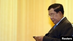 FILE - Cambodia's Prime Minister Hun Sen looks at his smartphone at a ceremony in Phnom Penh.