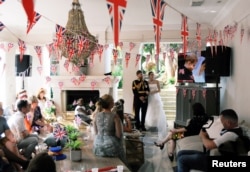 People watch Britain's Prince Harry and Meghan Markle during their wedding on television at a party in Durban, South Africa, May 19, 2018.