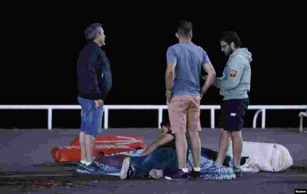 Seorang warga yang terluka berbaring di tanah dekat lokasi sebuah truk menabrak kerumunan massa di Nice, Perancis, dalam perayaan hari libur nasional Hari Bastille (15/7). (Reuters/Eric Gaillard)