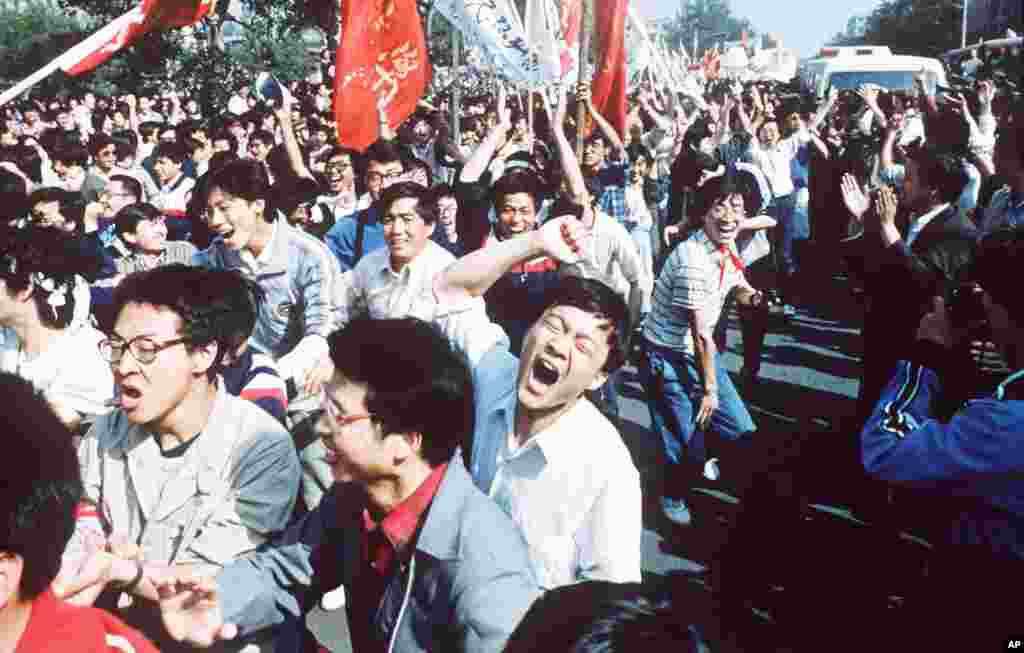 Para mahasiswa/i berseru setelah mendobrak blokade polisi dalam pawai pro-demokrasi ke Alun-alun Tiananmen di Beijing, 4 Mei 1989.&nbsp;(AP/S. Mikami)