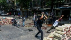 FILE - Anti-coup protesters test a slingshot-type weapon they have made to fight armed Myanmar security forces in Yangon, Myanmar, March 17, 2021.