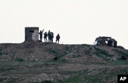 FILE - Fighters of People's Protection Units, or YPG, gather at their outpost west of the city of Kobani, northern Syria, Tuesday, Dec. 18, 2018.