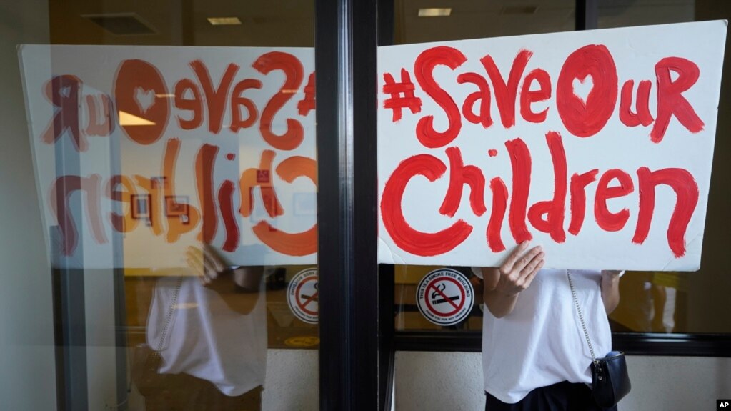 FILE - A protester, demonstrating against COVID-19 vaccine mandates, holds a sign outside the front windows of the Los Angeles Unified School District, LAUSD headquarters in Los Angeles, Sept. 9, 2021. (AP Photo/Damian Dovarganes, File) 