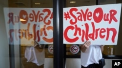 FILE - A protester, demonstrating against COVID-19 vaccine mandates, holds a sign outside the front windows of the Los Angeles Unified School District, LAUSD headquarters in Los Angeles, Sept. 9, 2021. (AP Photo/Damian Dovarganes, File) 