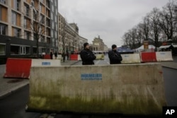 Armed police officers stand behind concrete blocks for protection near the Brandenburg Gate in Berlin, Friday, Dec. 23, 2016.