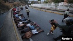 Orang-orang ditahan pasukan keamanan berbaring di jalanan setelah penjarahan merajalela di tengah pemadaman listrik yang meluas di Caracas, Venezuela, 10 Maret 2019 (foto: Reuters/Ivan Alvarado)