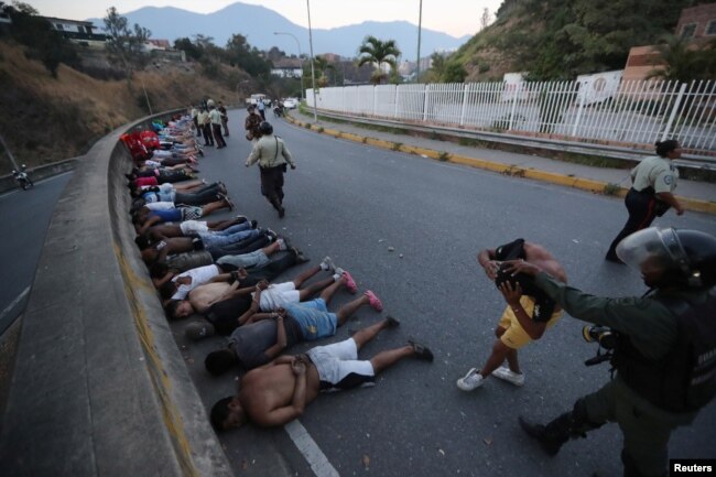 People detained by security forces lie on the street after looting broke out during an ongoing blackout in Caracas, Venezuela, March, 10, 2019.