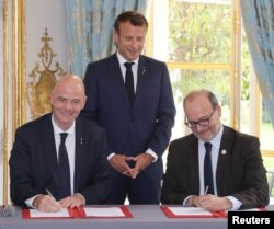 French president Emmanuel Macron stands during the signature of an agreement between FIFA president Gianni Infantino and AFD (French Development Agency) president Remy Rioux at the Elysee Palace, in Paris, June 4, 2019.