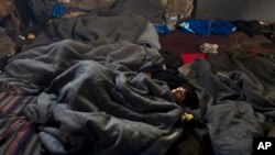 A migrant sleeps on the ground of an abandoned warehouse where he and other migrants took refuge in Belgrade, Serbia, Feb. 11, 2017.