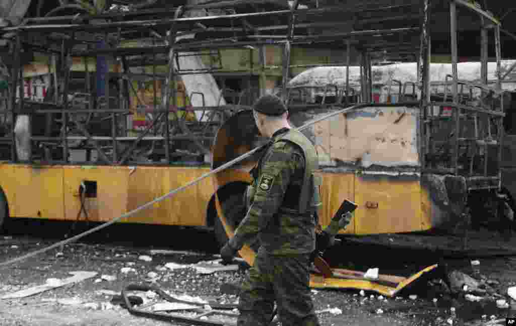 A Russia-backed separatist walks past a destroyed bus after a bus station was hit during a recent shelling between Russian-backed separatists and the Ukrainian government forces in Donetsk, Ukraine, Feb. 11, 2015.