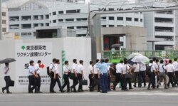 Polisi dan petugas pemadam kebakaran antre untuk divaksinasi COVID-19 dengan vaksin Moderna di bekas pasar ikan Tsukiji yang diubah menjadi situs pusat vaksinasi massal sementara di Tokyo, 16 Juni 2021. (Foto AP/Koji Sasahara, File)