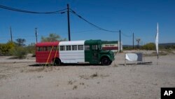 FILE - A bus painted in a Mexican flag motif and a banner with the Spanish farewell for "have a nice trip," serves as a roadside advertisement for a Chevron station, in Ajo, Arizona, April 4, 2017. In the past month, three large groups of migrants have been found in the desert near Ajo.