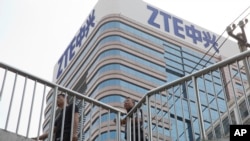 Men pass by a building of Chinese tech giant ZTE in Beijing, China, May 8, 2018.