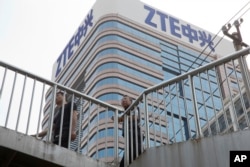 FILE - Men pass by a building of Chinese tech giant ZTE, in Beijing, China, May 8, 2018.