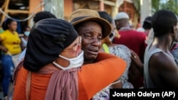 People cry during the search for those who are still missing in a house destroyed by the earthquake in Les Cayes, Haiti, Sunday, Aug. 15, 2021. (AP Photo/Joseph Odelyn)