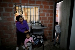 In this April 7, 2020, photo, Rosemary Paez Carabaja holds her daughter Laisa's hair as her son Leonardo enters to the room they rent in Buenos Aires, Argentina. (AP Photo/Natacha Pisarenko)