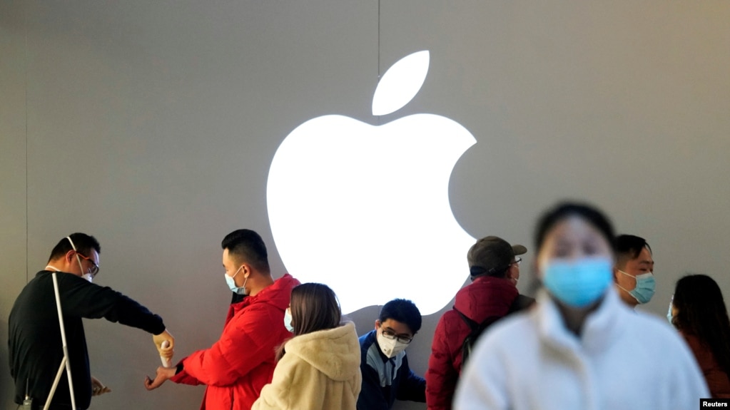 资料照：戴着口罩的人们排队等候测量体温进入一家上海的苹果商店。（2020年2月21日）