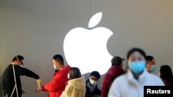 Orang-orang mengenakan masker antre untuk diperiksa suhu di sebuah Apple Store di Shanghai, China, 21 Februari 2020. (Foto: Reuters)