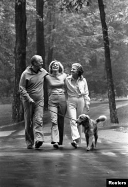 FILE - Former U.S. President Gerald R. Ford (left), daughter Susan (center) and his wife first lady Betty Ford (right) and their dog Liberty walk at the presidential retreat Camp David in Maryland, Aug. 7, 1976.