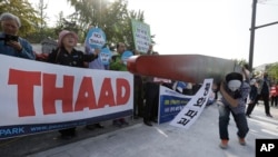 Protesters carry a mock missile symbolizing an advanced U.S. missile defense system called Terminal High-Altitude Area Defense, or THAAD, during a rally to oppose a plan to deploy the THAAD in front of the Defense Ministry in Seoul, South Korea, Oct. 20, 2016.