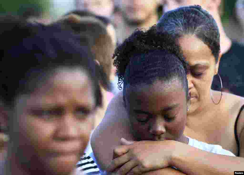 People grieve during a vigil for victims behind the theater where a gunman opened fire on moviegoers in Aurora, Colorado July 20, 2012.