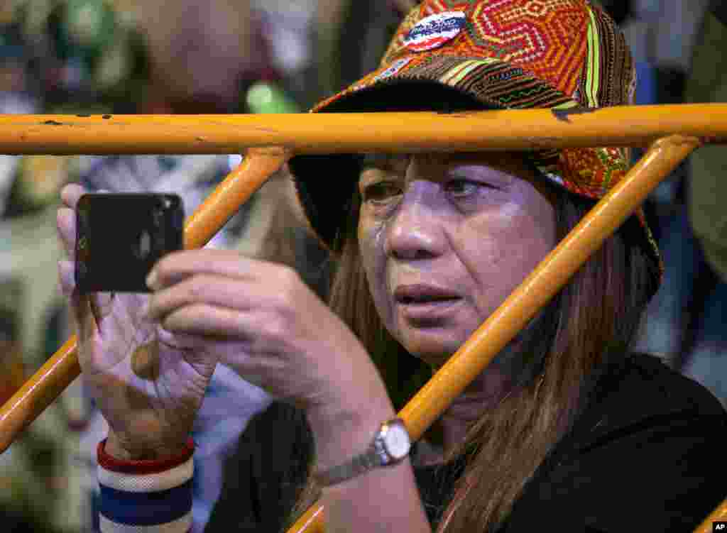 A Thai anti-government protester cries and takes picture during a condolence ceremony for Yuthana Ong-art, who was shot and killed on Friday night, in Bangkok, Thailand.