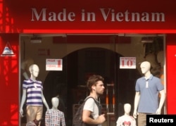 FILE - A tourist walks past a clothes shop in Hano,i October 3, 2014.