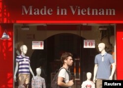 A tourist walks past a clothes shop in Hanoi October 3, 2014. Growth in exports driven by manufacturing could give Vietnam a trade surplus.