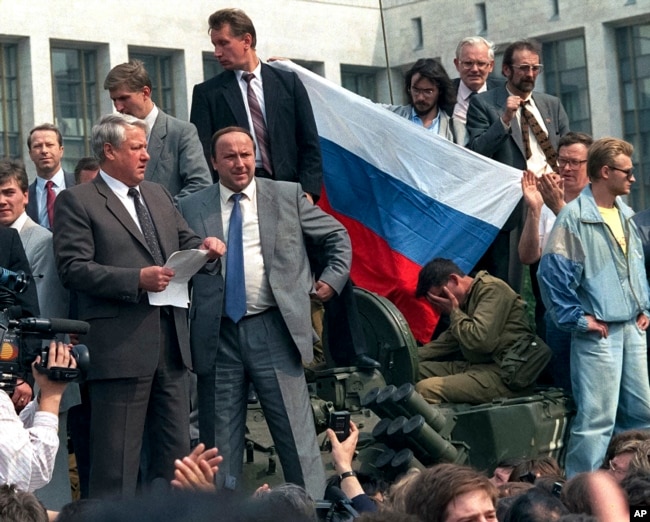 FILE - In this Aug. 19, 1991, photo, Boris Yeltsin, foreground left, at the time president of the Russian constituent republic within the Soviet Union, addresses a crowd standing atop of a tank in front of the Russian Government Building.