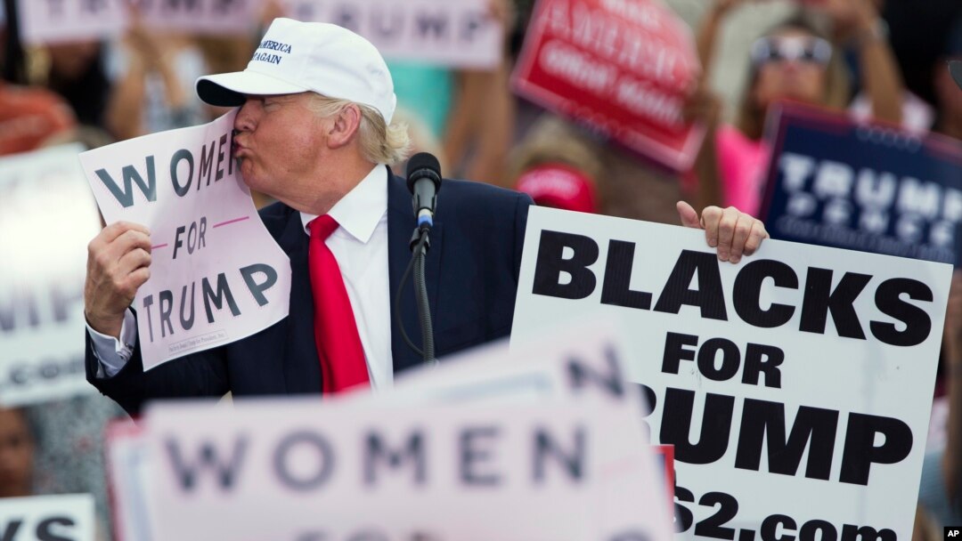 Republican presidential candidate Donald Trump kisses a "Women for Trump" sign during a campaign rally, Wednesday, Oct. 12, 2016, in Lakeland, Florida. 